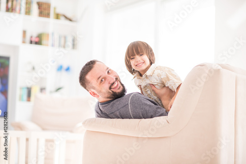 Father playing with his little son on sofa at home