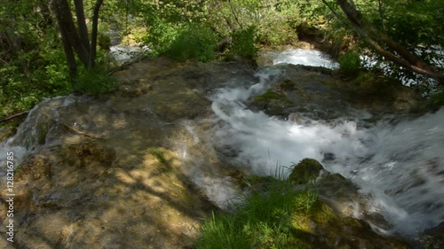 The camera follows the course of a mountain creek through a forest down the mountain with its cascades and rapids photo