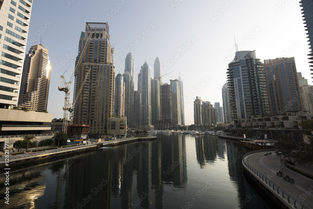 Obraz premium Architecture theme. Panoramic view with modern skyscrapers and water pier of Dubai Marina at sunrise,, United Arab Emirates. Luxurious property.