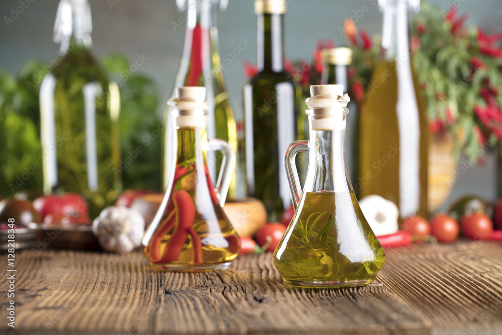 Olive oil and rosemary, chili pepper, many different tomatoes, garlic, red, white, green pepper on old wooden table. Extra virgin olive oil cruets and flavored olive oils with rosemary and chili. Olive oil and rosemary, chili pepper, many different tomatoes, garlic, red, white, green pepper on old wooden table. Extra virgin olive oil cruets and flavored olive oils with rosemary and chili.