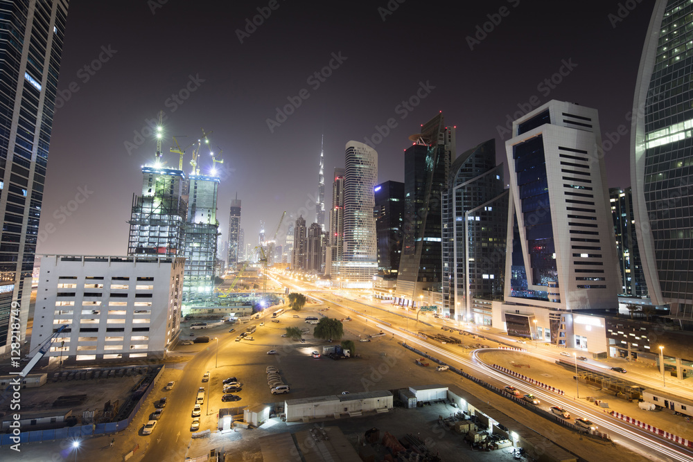 Architecture theme. Modern corporate city on the desert by night. Aerial view. Big construction site. Building on the desert. Oasis of the future. Beautiful night shot of Dubai Skyline illuminated.