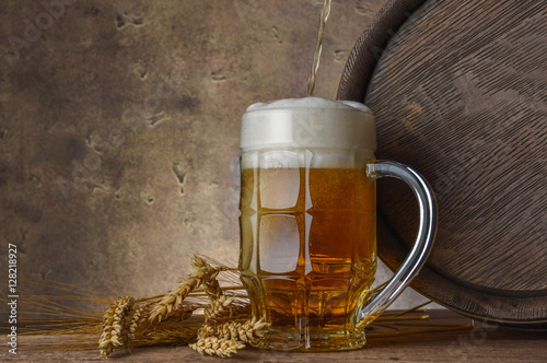 beer mug with wheat ears and wooden barrel on a dark wall background, pour beer 