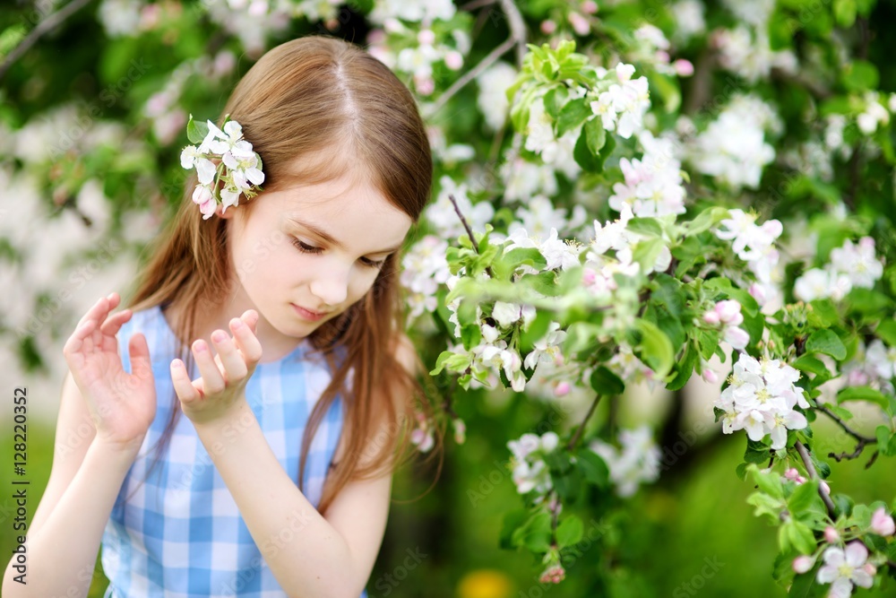 Adorable little girl in blooming apple tree garden on spring day Adorable little girl in blooming apple tree garden on spring day