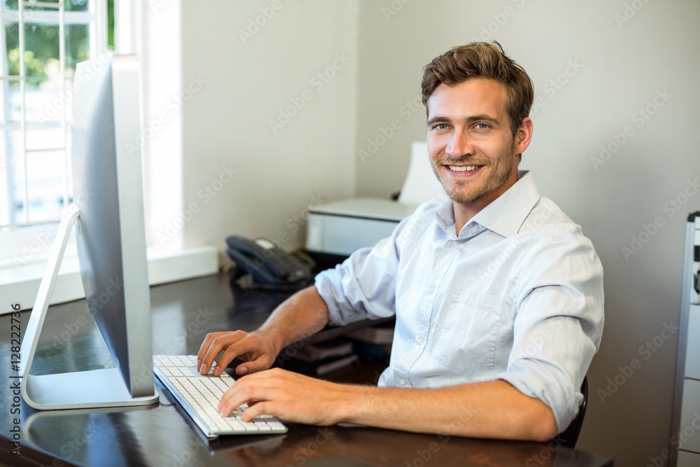 Young man working on computer at desk in office Young man working on computer at desk in office