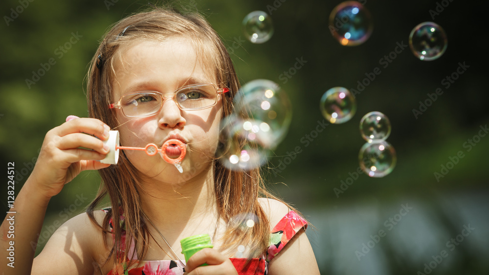 Little girl having fun blowing soap bubbles in park. Little girl having fun blowing soap bubbles in park.