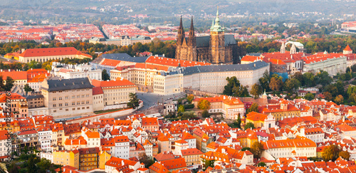 Prague Castle complex with gothic St Vitus Cathedral in the evening time illuminated by sunset, Hradcany, Prague, Czech Republic. UNESCO World Heritage. Panoramic aerial shot from Petrin Tower. photo