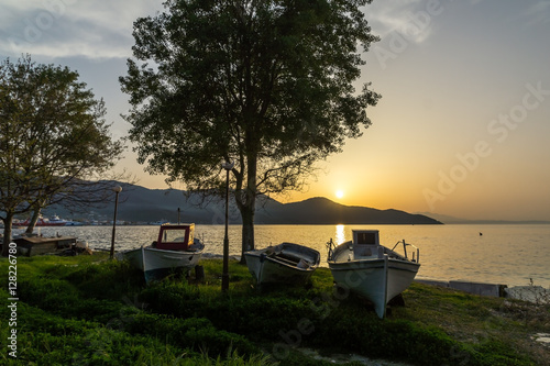 Sunset seascape with tree and old boat on embankment of Thassos town, East Macedonia and Thrace, Greece 