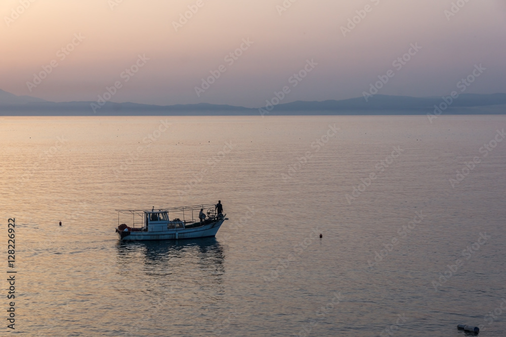 Amazing Sunset view with fishing boat in the sea of Thassos town, East Macedonia and Thrace, Greece 
