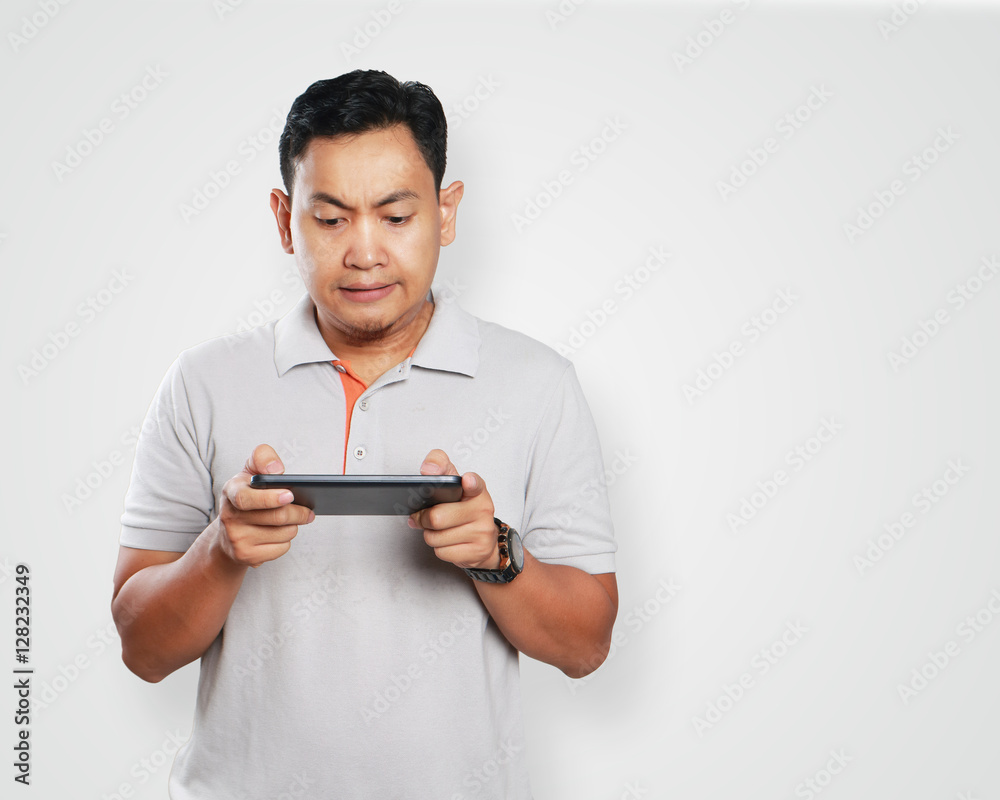 Funny Young Asian Guy Playing Games on Tablet