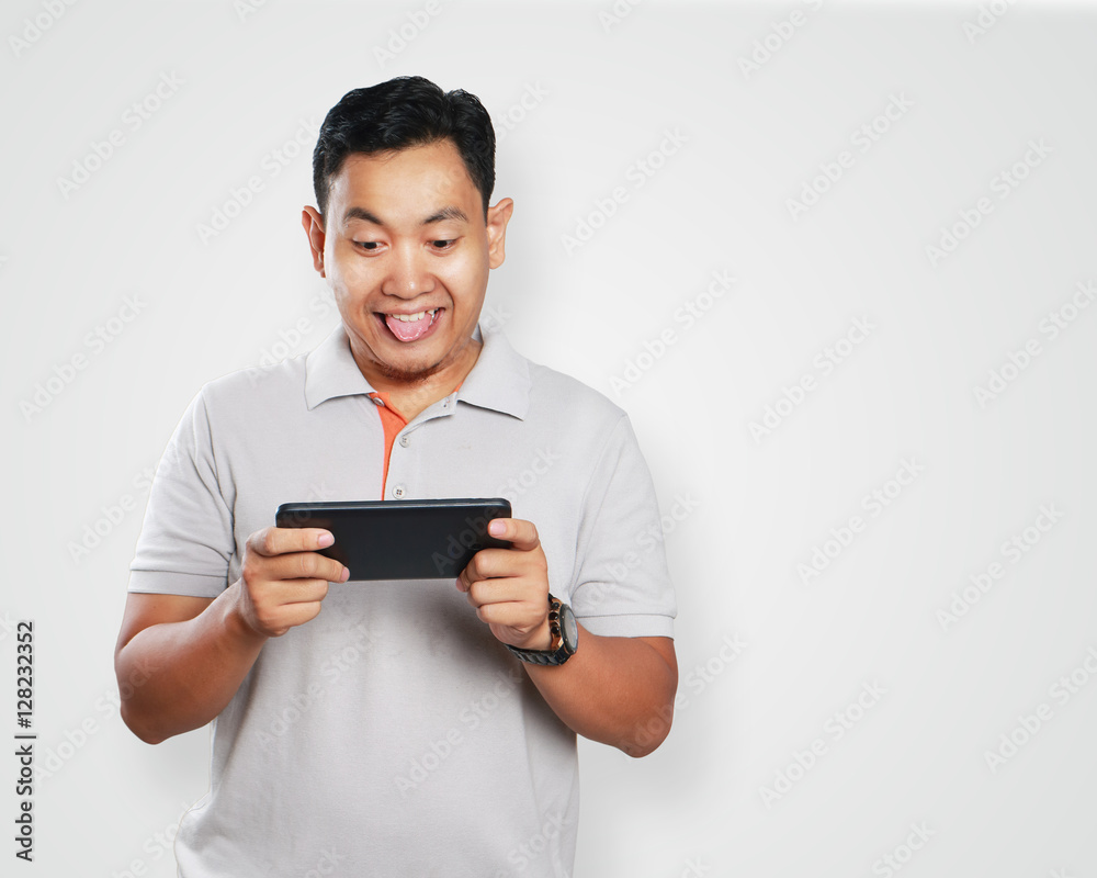 Funny Young Asian Guy Playing Games on Tablet Funny Young Asian Guy Playing Games on Tablet