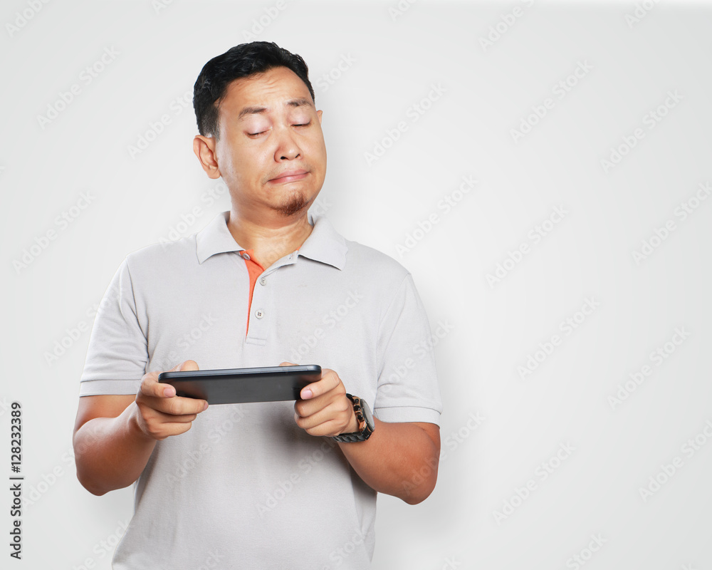 Funny Young Asian Guy Playing Games on Tablet Funny Young Asian Guy Playing Games on Tablet