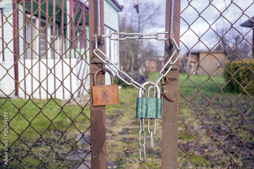 Two old padlocks and a chain on a rusty fence
