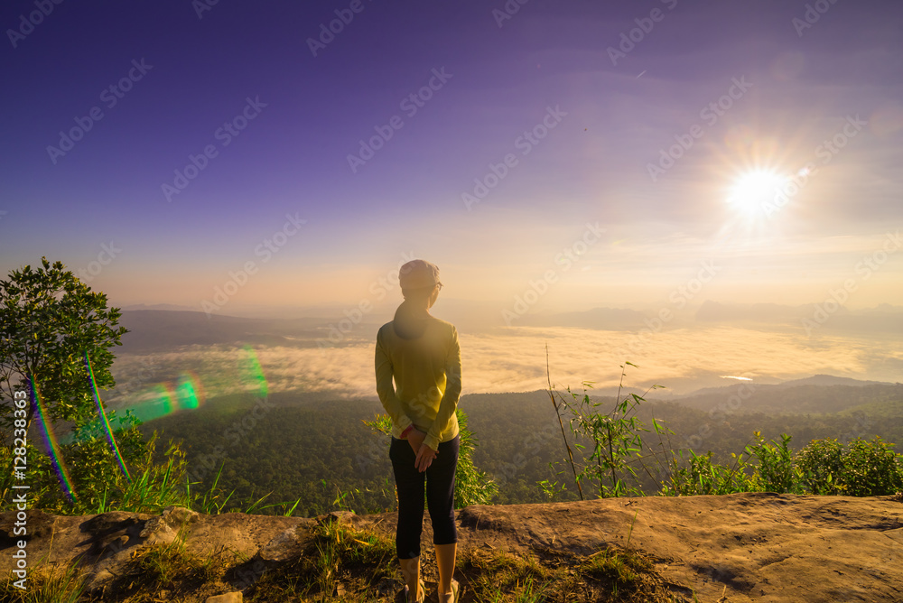 Happy Young Woman Hiker With Open Arms Raised at Sunset on Mountain Peak