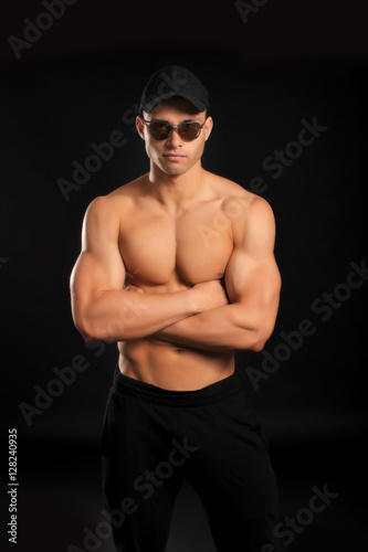 handsome bodybuilder man with a naked torso showing muscles in cap and glasses