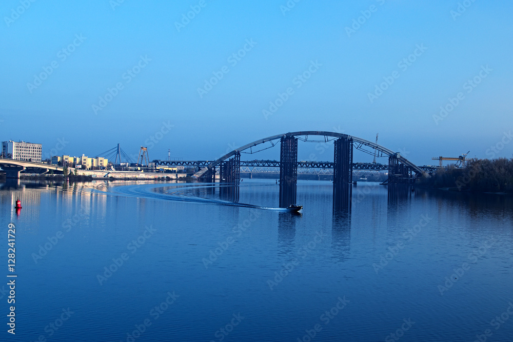 Naklejka premium KYIV, UKRAINE – 16 November 2016: Morning view to the unfinished bridge. City landscape. Motor boat floats on the Dnieper 