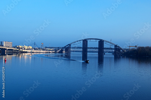 KYIV, UKRAINE – 16 November 2016: Morning view to the unfinished bridge. City landscape. Motor boat floats on the Dnieper 