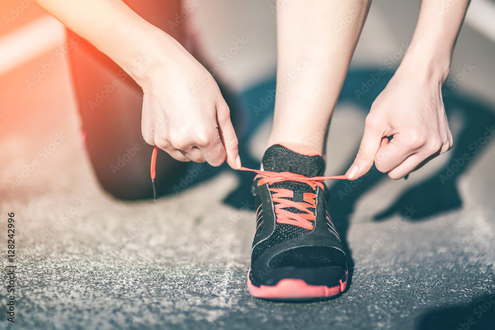 Young Woman Runner tying his sport shoes on a running track. Shoelaces, Urban jogger