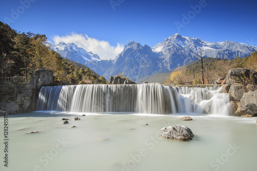 Waterfall on foreground and Jade Dragon Snow Mountain on background - Yunnan, China
