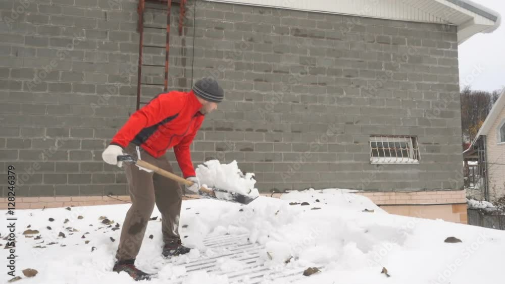 Slow Motion Man with a shovel removing snow from a roof. Caucasian men using to shovel heavy snow off roof. People with plastic shovel tool push clean snow from roof. Slow Motion Man with a shovel removing snow from a roof. Caucasian men using to shovel heavy snow off roof. People with plastic shovel tool push clean snow from roof.