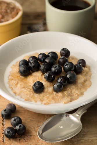 Bowl of Breakfast Porridge and Blueberries on Wooden Background