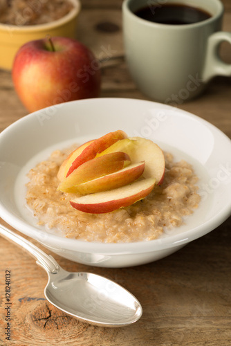 Bowl of Oatmeal and Sliced Apples on Wooden Background