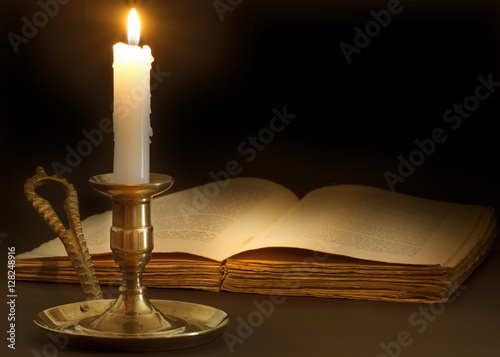 Old book lit by the flame of a candle