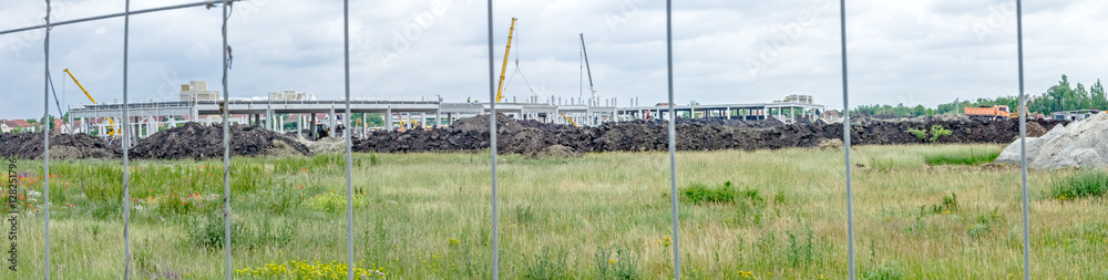 Panoramic view on the construction site through a fence wire