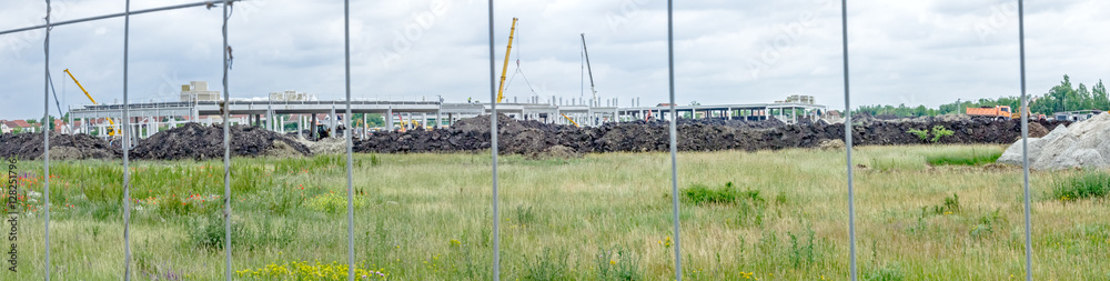 Panoramic view on the construction site through a fence wire Panoramic view on the construction site through a fence wire