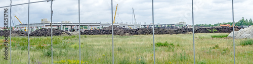 Panoramic view on the construction site through a fence wire