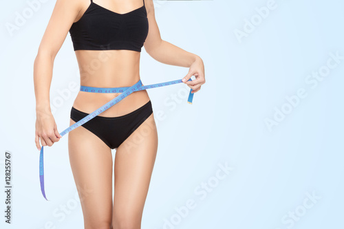 woman measuring her waist by blue measure tape