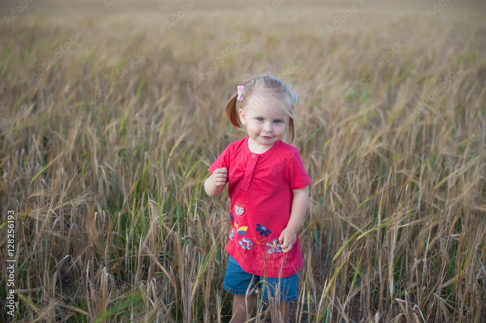 Little fair-haired girl playing in the rye field