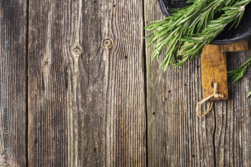 Fresh cut rosemary in a bundle in black wicker basket on simple dark wooden background. View from above. selective focus Fresh cut rosemary in a bundle in black wicker basket on simple dark wooden background. View from above. selective focus