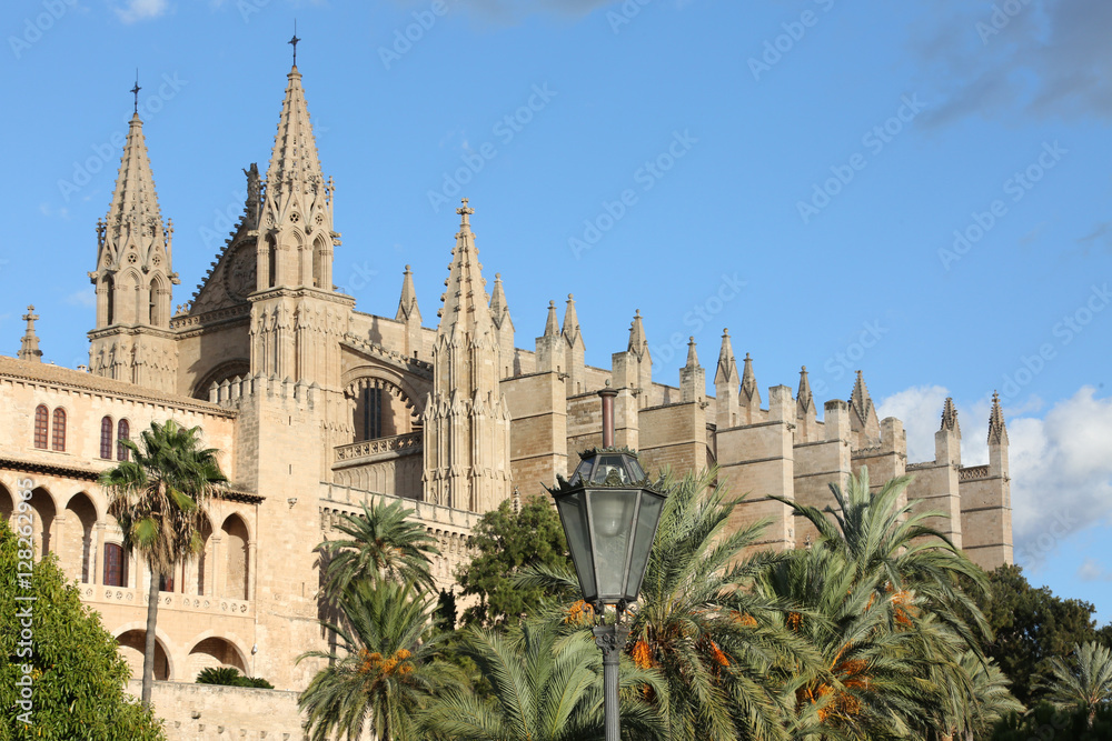 the cathedral of Palma de Mallorca with palm trees and a lantern in front of it