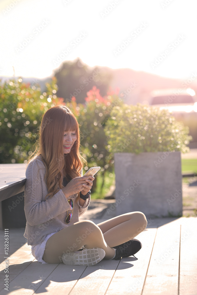 Obraz premium Happy woman smiling and using a smartphone