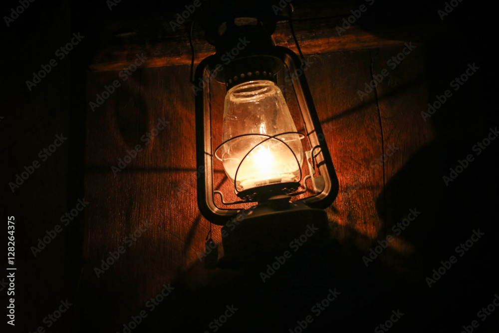 a glowing lantern on a woody wall in the darkness