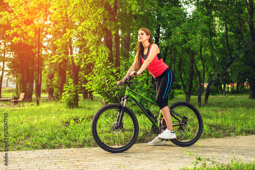 Sports happy girl over a bicycle in the park © Artem