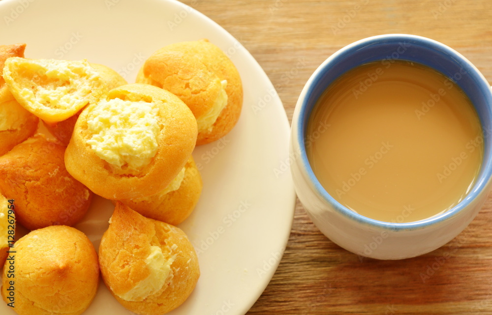 vanilla cream puff on dish and coffee cup vanilla cream puff on dish and coffee cup