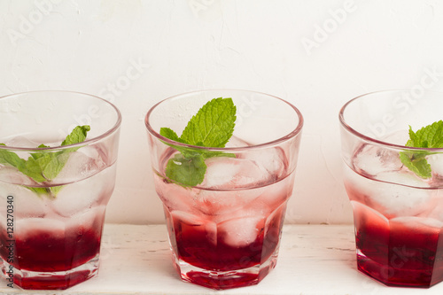 Three glasses with red drink with mint and ice on a white background