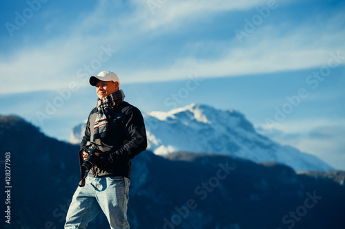 handsome man travel in winter mountains with camera