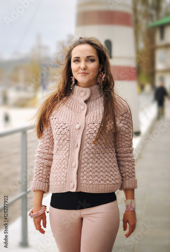Young happy woman hike near lighthouse, happy, fresh and smiling, dressed in casual gentle pink sweater