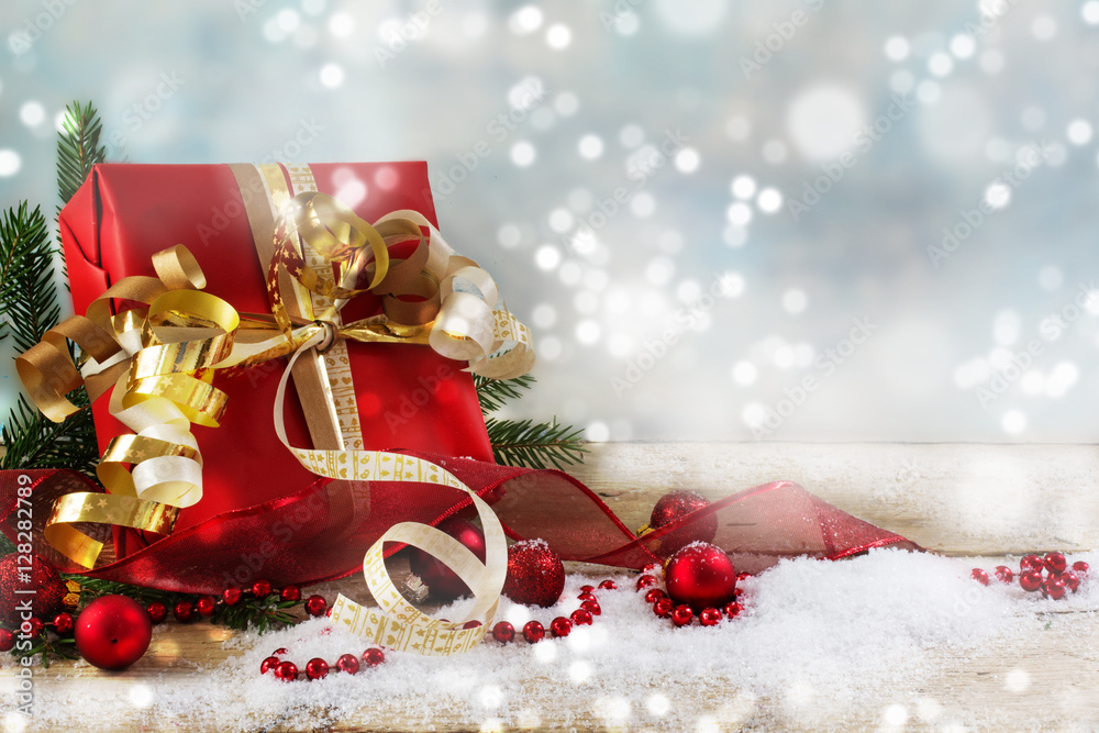 Φωτογραφία christmas and new year gift with red paper, golden ribbons and baubles, snowy ba