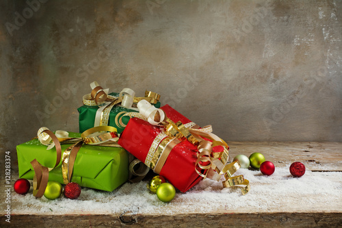 christmas and new year gifts in green and red paper, golden ribbon an baubles on rustic wood
