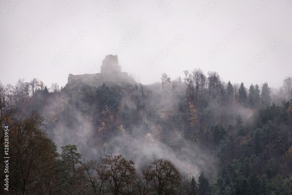 Mysterious medieval castle ruins in fog on top of hill