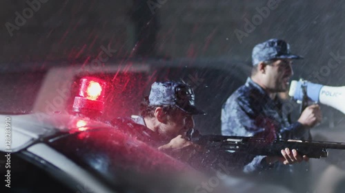 Policeman speaks on rupor. Another armed policeman takes aim to the offender. Police surrounding . photo