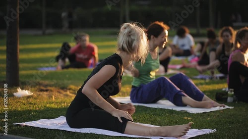 Yoga woman on green grass.. big group of adults attending a yoga class outside in park