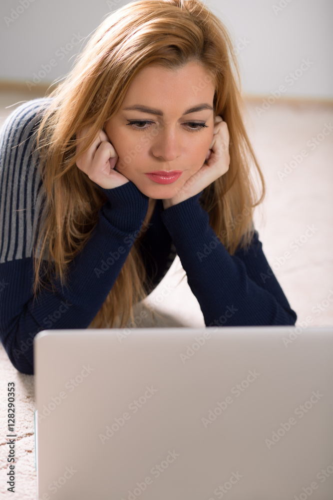 Beautiful woman lying on her floor at home and using notebook Beautiful woman lying on her floor at home and using notebook