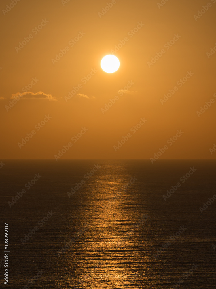 A view of a golden sunset over the sea. The light of the sun reflected in the water as the beam path.