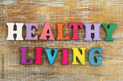 Healthy living written with colorful letters on rustic wooden surface

