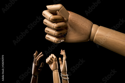 Hands manifest under a large closed fist.  About racism. Isolated on black background. With copy space text. Studio shot. photo