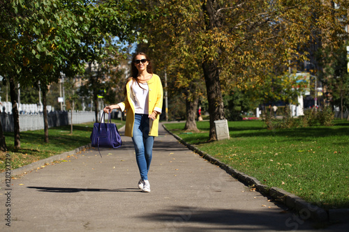 Happy woman in yellow coat walking autumn street © Andrey_Arkusha